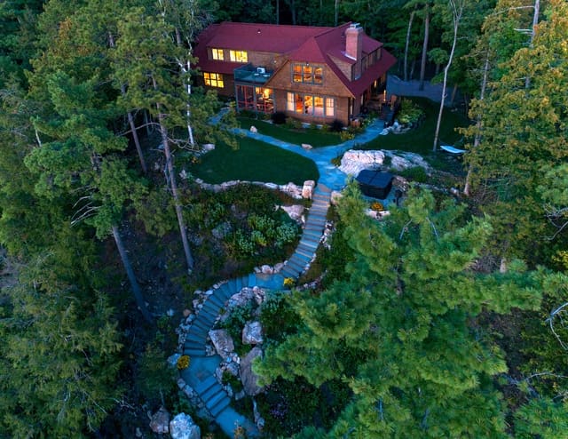 Aerial view of a lakeside home at dusk with a winding stone path through landscaped gardens, highlighting residential landscape design and custom build work.