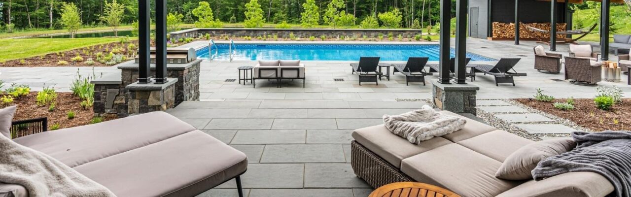 Luxury outdoor patio and pool area with lounge seating and landscaped surroundings.