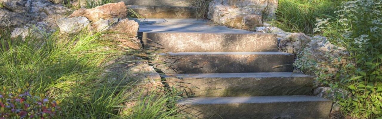 Stone landscape steps surrounded by greenery and natural plantings.